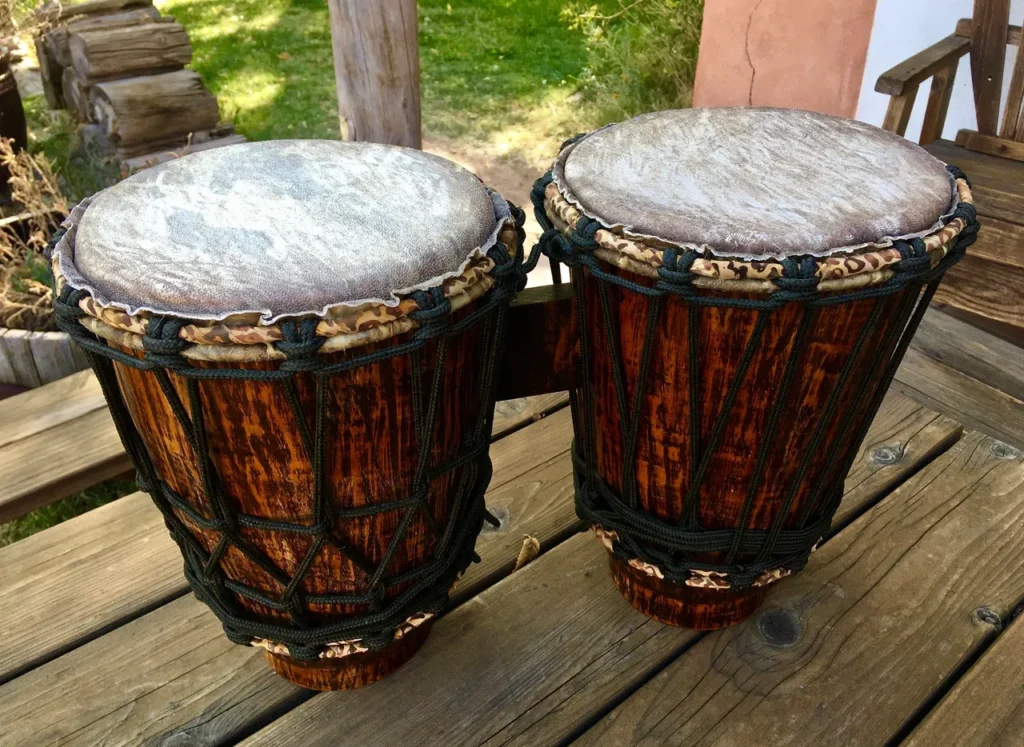 Two djembe drums, traditional African percussion instruments, sitting on a wooden deck.