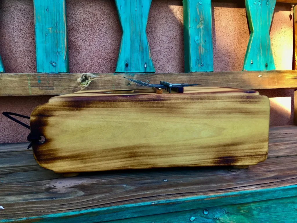 An African drum sitting on a wooden bench.