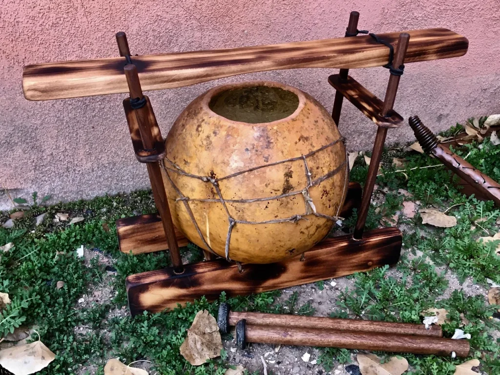 A wooden pot with a wooden handle and a lamellaphone.