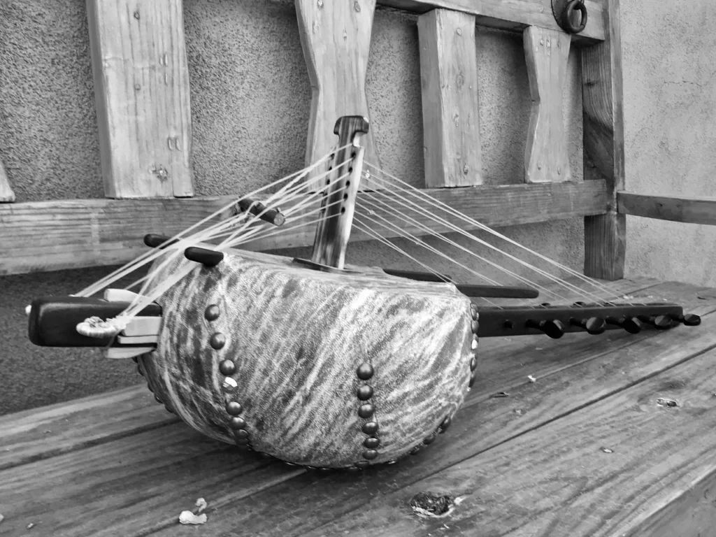 A black and white photo of an Ngoma instrument on a wooden bench.