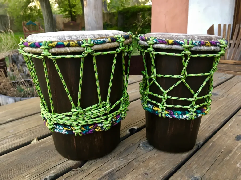 Two djembe drums on a wooden table.