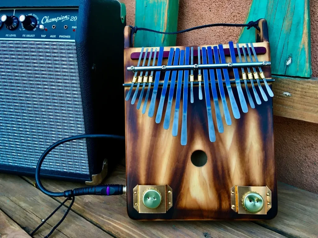 A gourd ukulele sits on a wooden table next to a guitar amp.