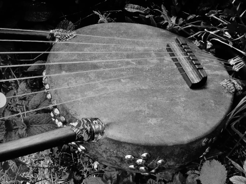 A black and white photo of an African drum in the grass.