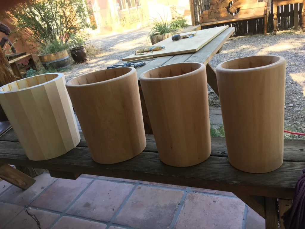 Three wooden planters, made from Ilimba wood, sitting on a wooden bench.