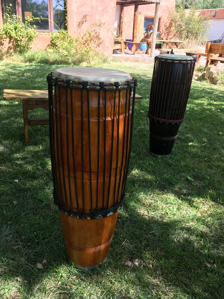 Two wooden Ilimba djembe drums sitting on the grass.