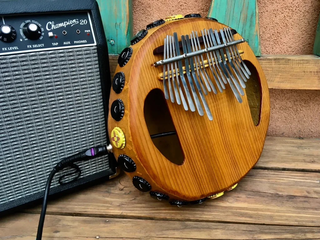 Amongst the collection of gourd instruments, a wooden ukulele sits gracefully next to a guitar amplifier.