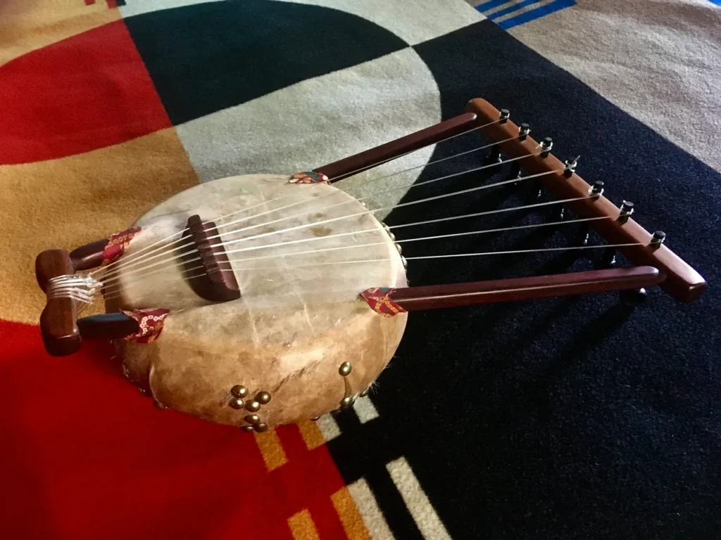 An African drum is sitting on a colorful rug.