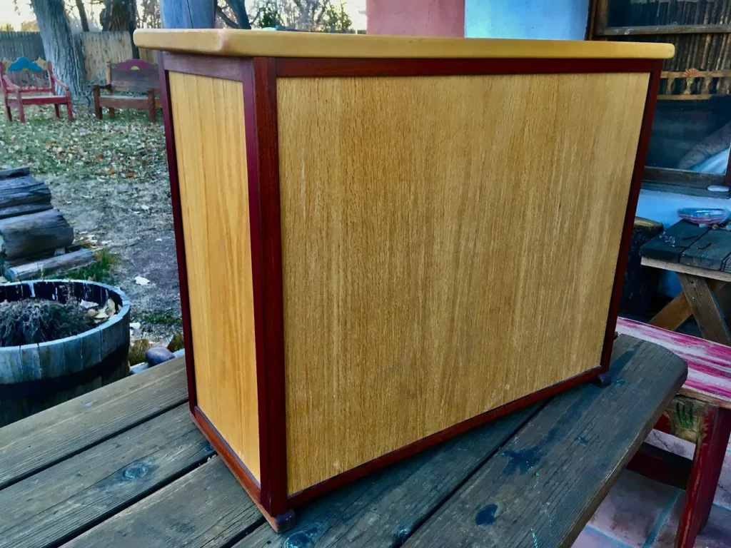 A wooden cabinet with a Kalimba on top, sitting on a wooden table.