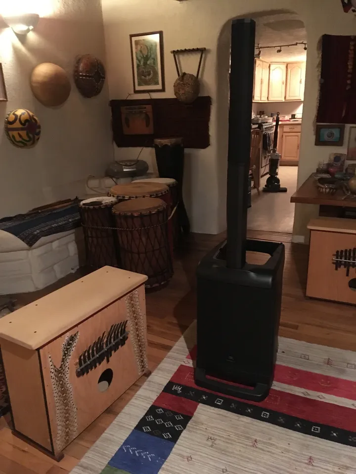 A living room with a large speaker in the middle of the room, featuring an African drum.