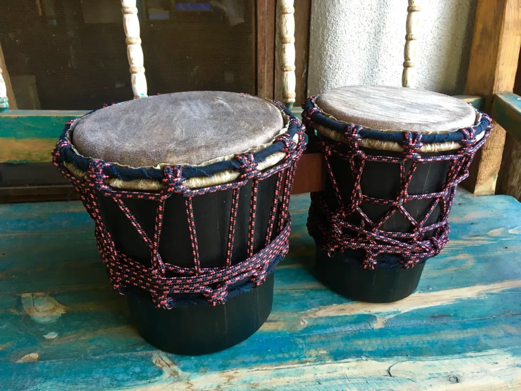 Two djembe drums, traditional African instruments, sitting on a wooden bench.