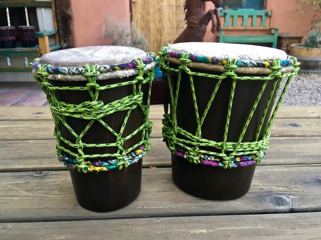 Two djembe drums on a wooden table.