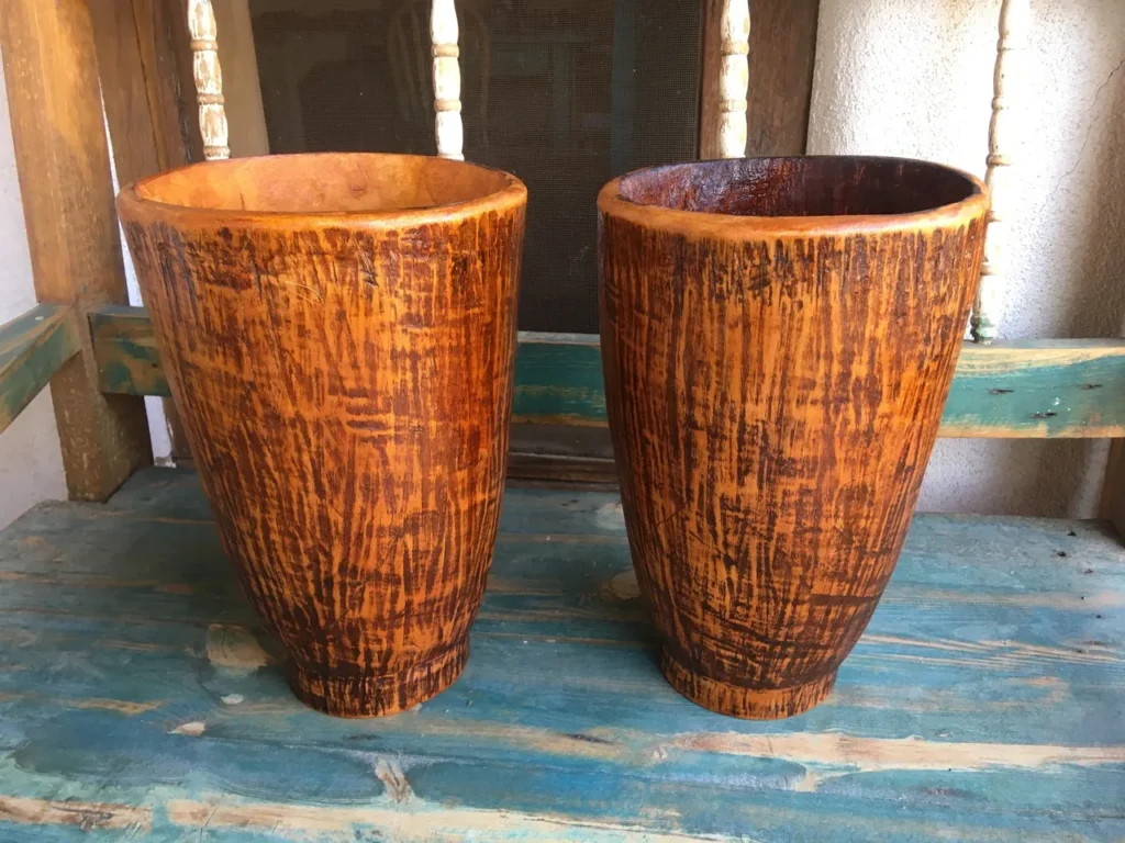 Two wooden vases sitting on an African harps.