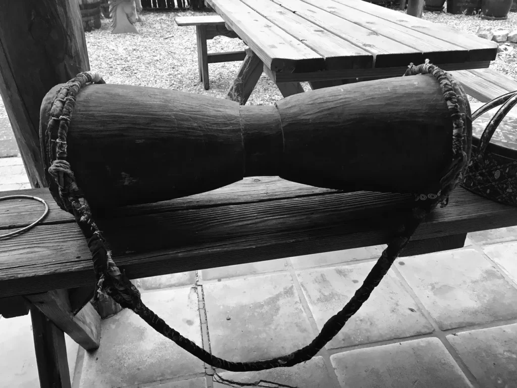 A black and white photo of a wooden drum on a table.