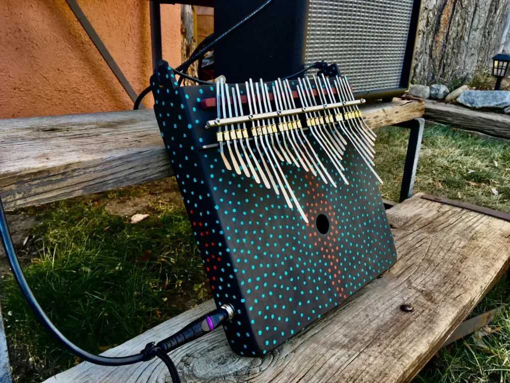 A polka dot ukulele, called a Kongoma, sitting on a wooden bench.