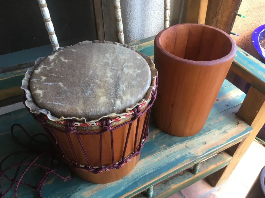 A wooden djembe, an African harp, sitting on a wooden bench.