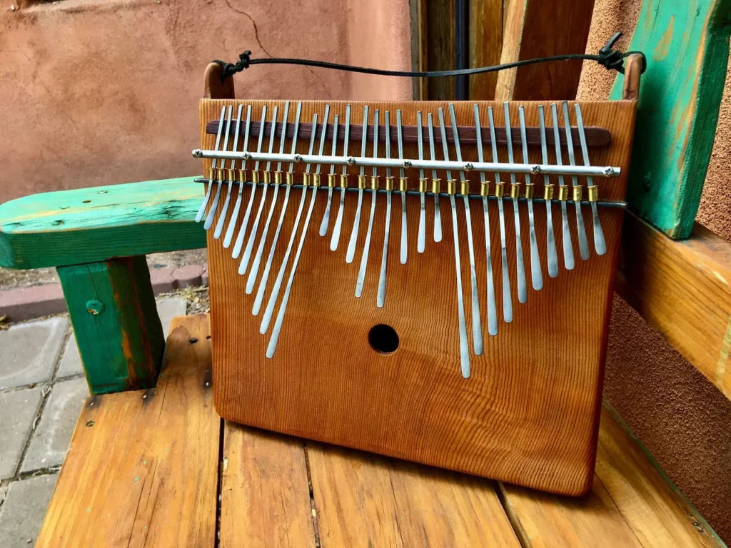 A wooden xylophone, also known as Kongoma or Marimbula, sitting on a wooden bench.