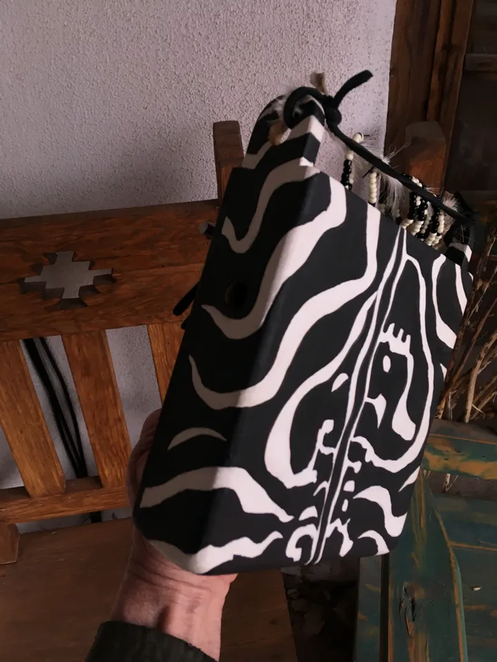 A person holding a black and white zebra print bag inspired by Ngoma, African music.