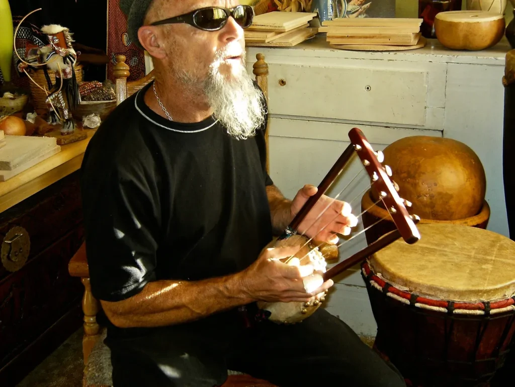 A man with a beard is playing an African drum.