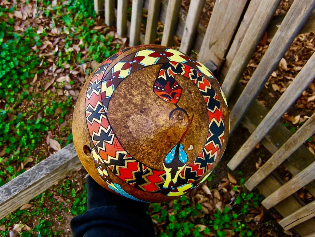 A person holding a Ngoma drum adorned with colorful designs, creating vibrant African music.