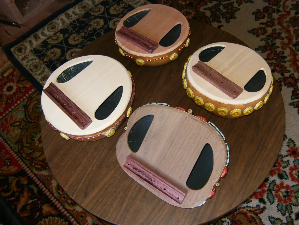 Four wooden drums, including the Ilimba, sitting on a table.