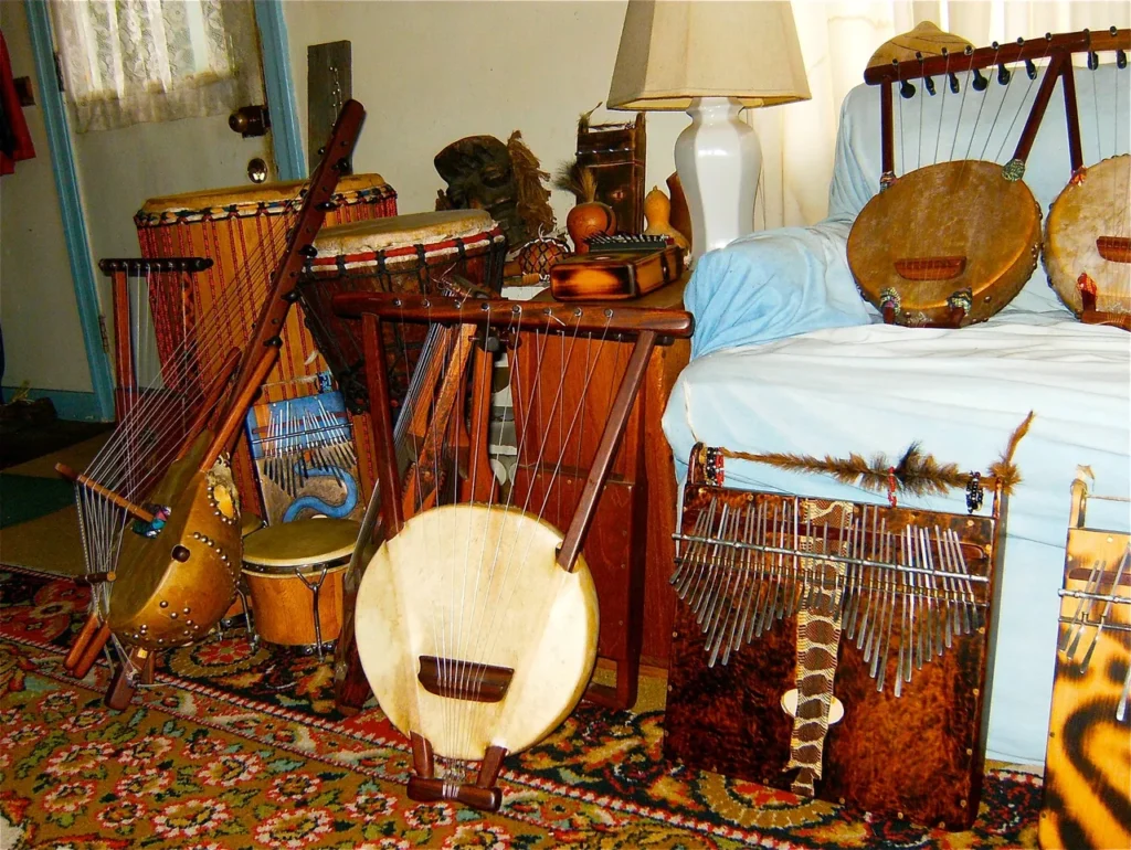 A group of musical instruments - a Kalimba and an African drum - on a bed.