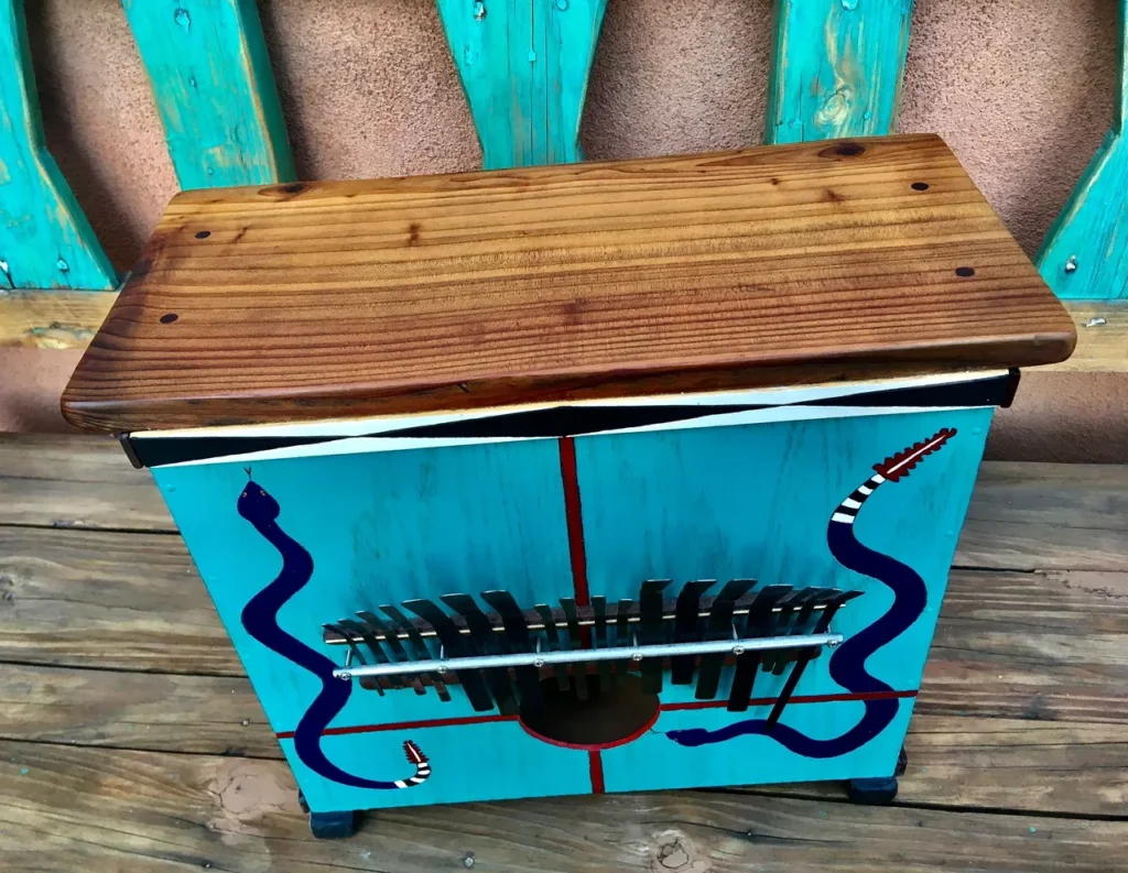 A wooden box with a snake painted on it, reminiscent of African drum design.