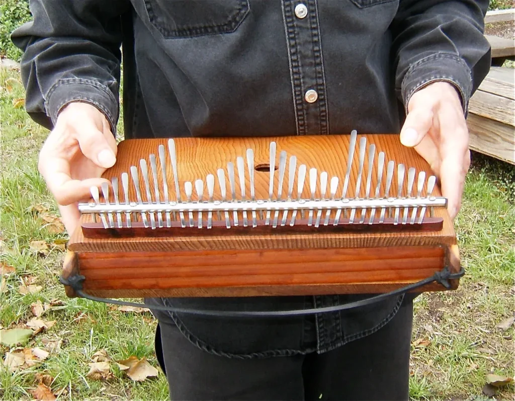 A man holding a wooden box filled with nails, known as kongoma.