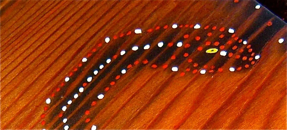 An image of a painted wooden surface with dots on it, featuring Kongoma.