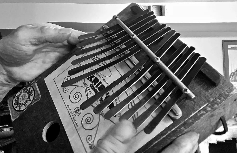 A black and white photo of a person holding an accordion, playing Ngoma, a traditional African music instrument.