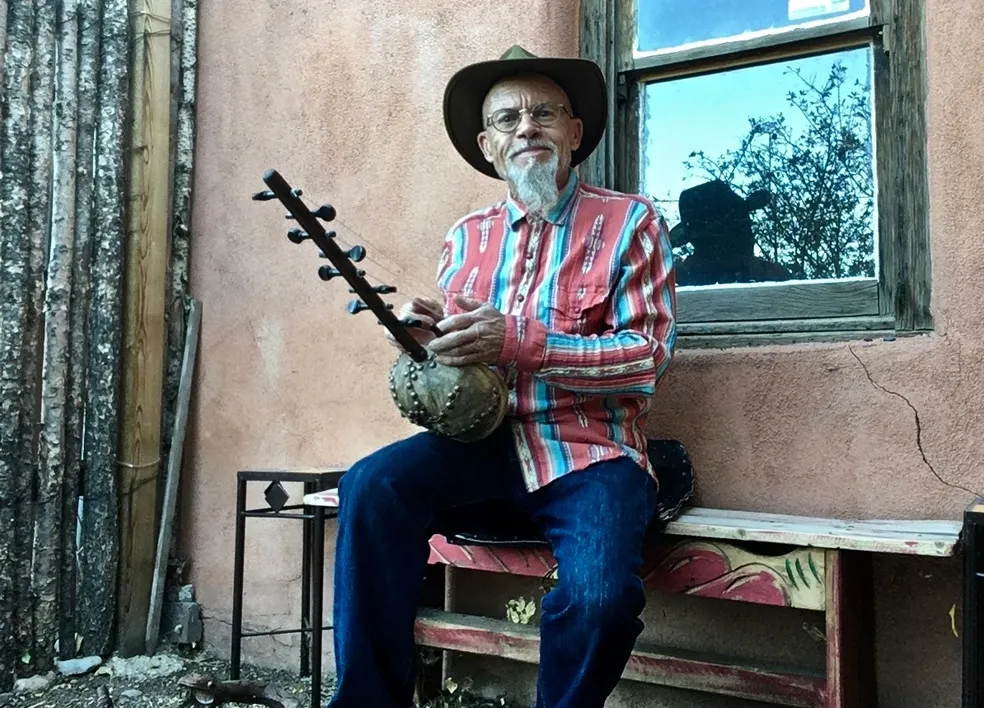 A man playing Ngoma on a bench.