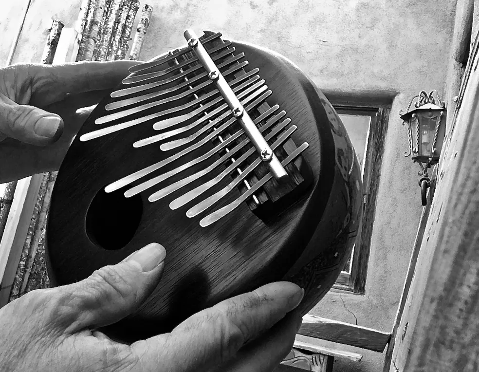 A black and white photo of a person holding a xylophone during an African music performance.