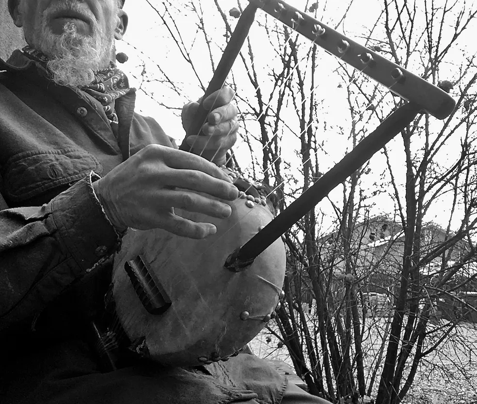 A man sitting on a bench playing a Kalimba.