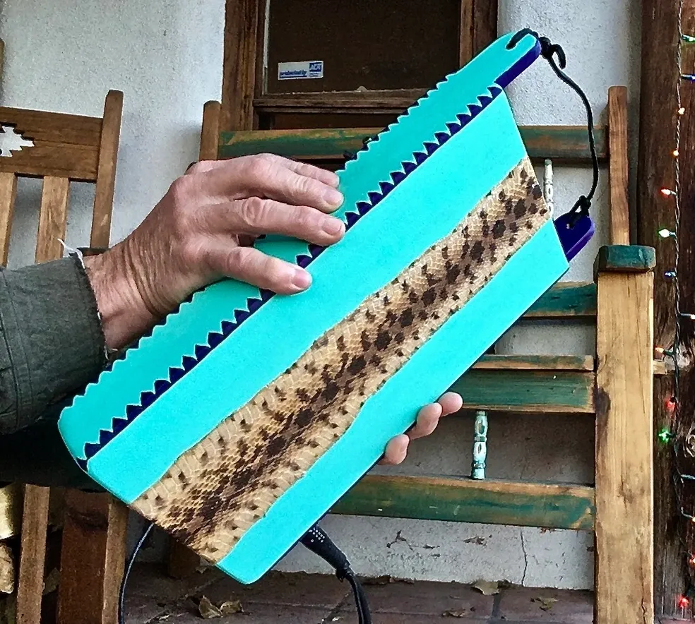 A person holding up a blue and brown leather case containing gourd instruments.