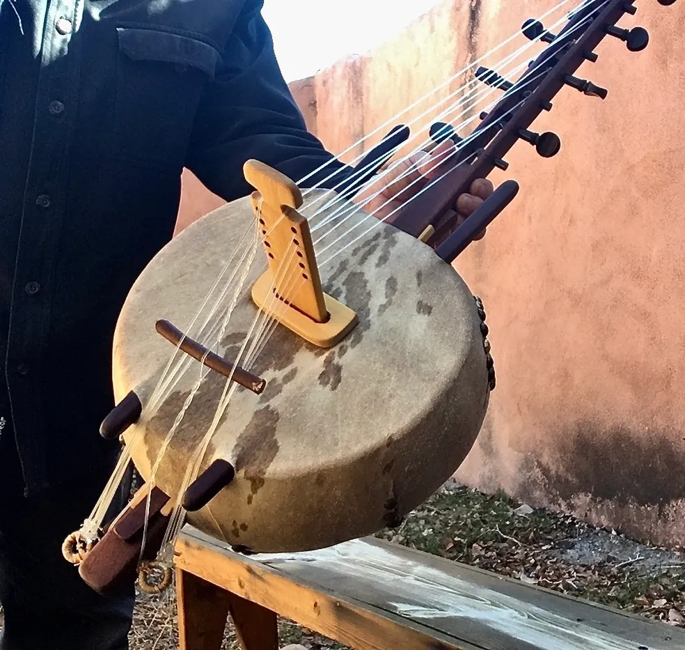 A man is holding up a Ngoma, an African musical instrument made of wood.